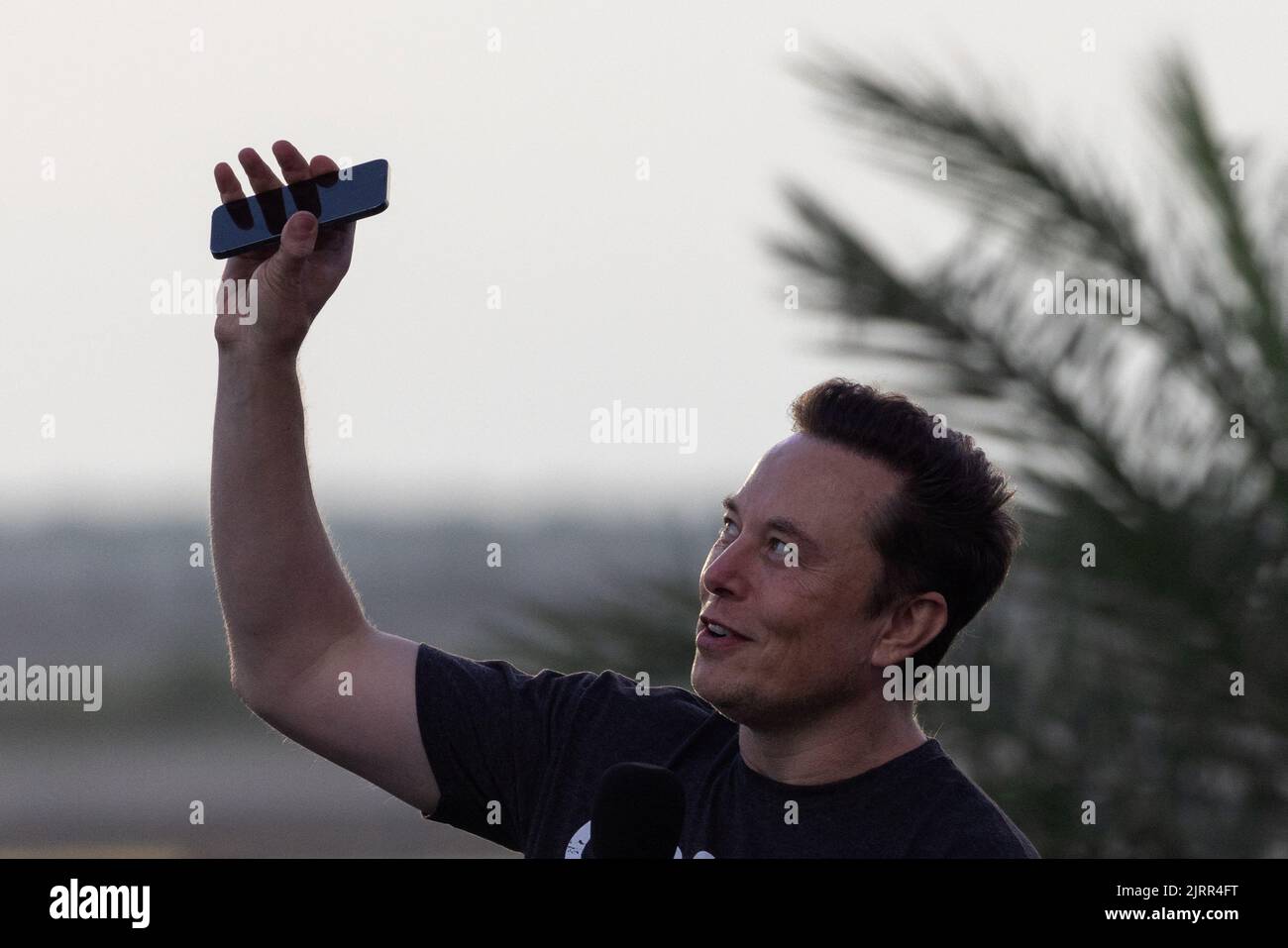 Elon Musk, ingénieur en chef de SpaceX, lève son téléphone vers le ciel lors d'une conférence de presse conjointe avec Mike Sievert, PDG de T-Mobile (non représenté) à la base aérienne SpaceX, à Brownsville, Texas, États-Unis, 25 août, 2022. REUTERS/Adrees Latif Banque D'Images