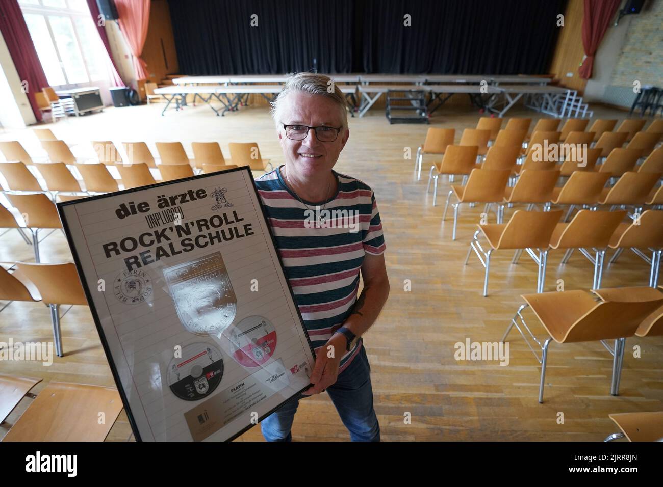 Hambourg, Allemagne. 07th juillet 2022. Le janitor André Schulz se tient dans l'auditorium de l'école secondaire Albert Schweitzer, en tenant le prix de platine pour le CD MTV-ungged du groupe Die Ärzte. L'école est devenue une école de rock'n'roll il y a 20 ans lorsque le groupe Die Ärzte enregistra son concert MTV-unplugged avec l'orchestre de l'école dans l'auditorium de 31 août 2002. L'école bénéficie encore aujourd'hui de cet événement musical. Depuis lors, par exemple, le tournage a eu lieu régulièrement au lycée. Credit: Marcus Brandt/dpa/Alay Live News Banque D'Images