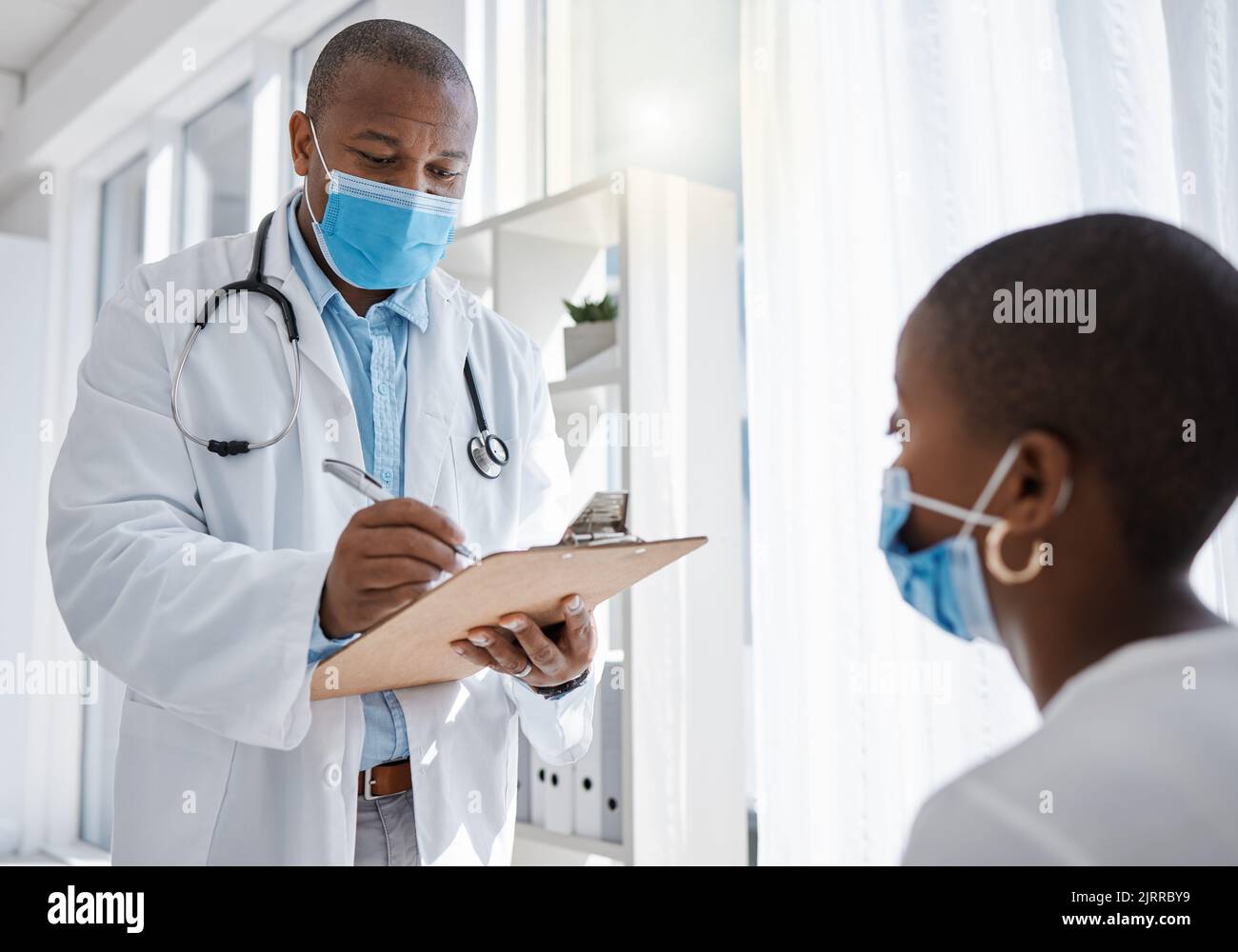 Covid médecin ou travailleur médical consultant un patient et écrivant des informations sur la santé à l'hôpital. Homme de santé travaillant sur l'assurance, le papier ou Banque D'Images