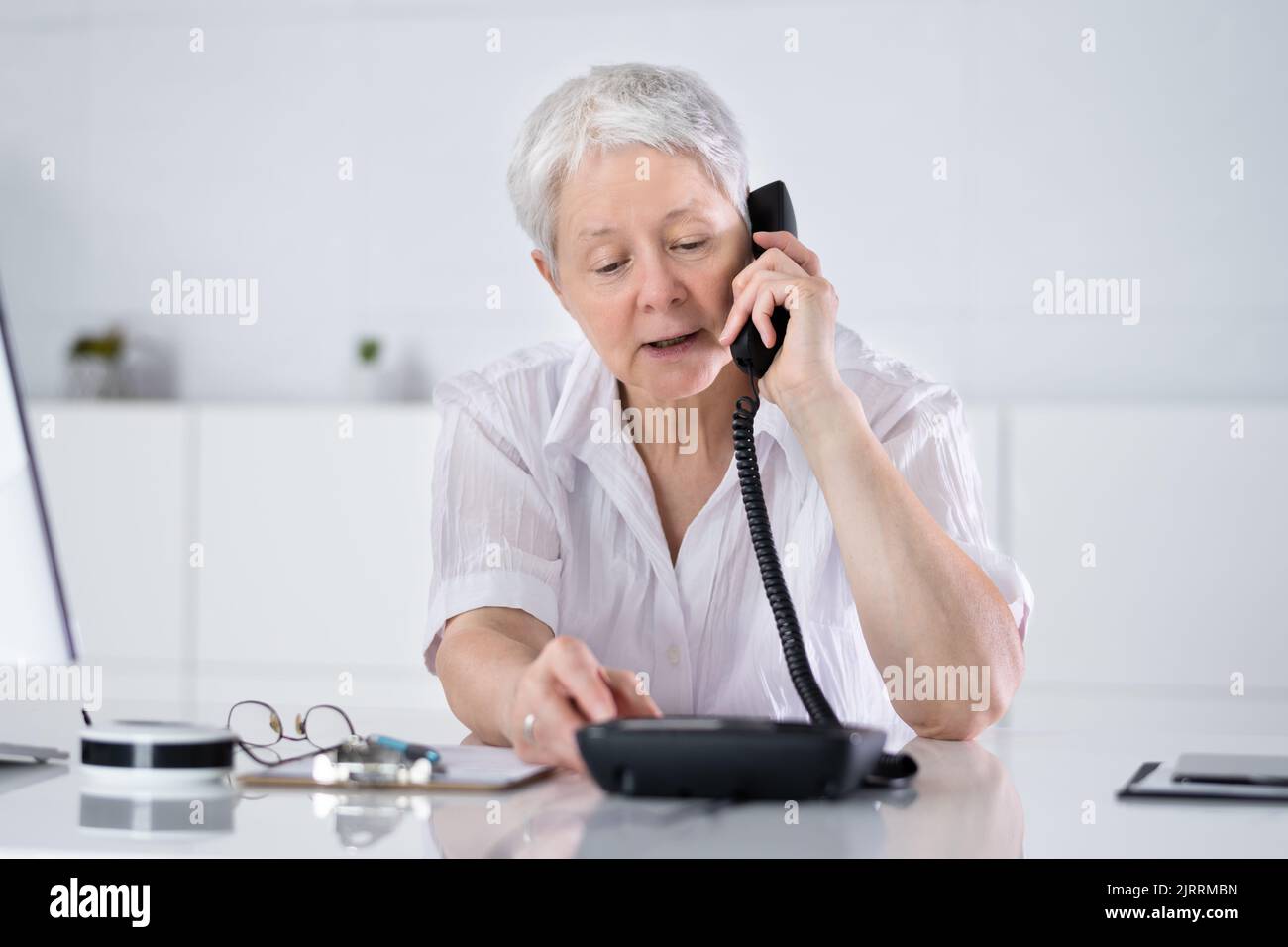 Femme d'affaires effectuant Un appel depuis un téléphone fixe au bureau au bureau Banque D'Images