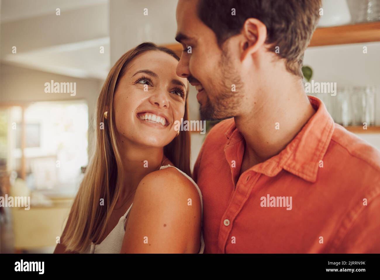 Couple, souriant et amoureux ayant un agréable moment romantique dans la cuisine à la maison. Homme et femme passant du temps libre affectueux ensemble, heureux et Banque D'Images