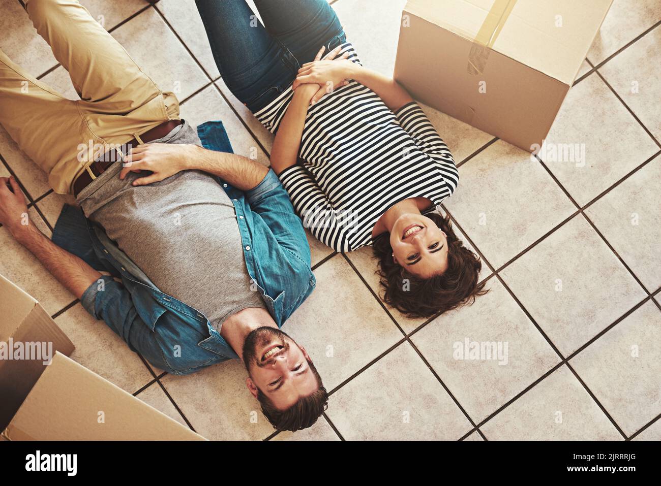 Le premier jour de notre nid d'amour. Un jeune couple heureux se détendant au sol de leur nouvelle maison. Banque D'Images