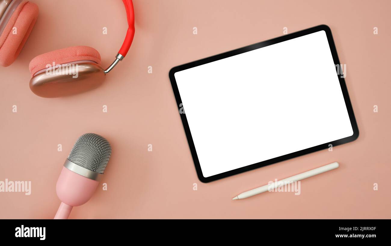 Tablette numérique plate, casque sans fil et microphone sur fond rose. Radio, podcasts, blogging et concept de technologie Banque D'Images