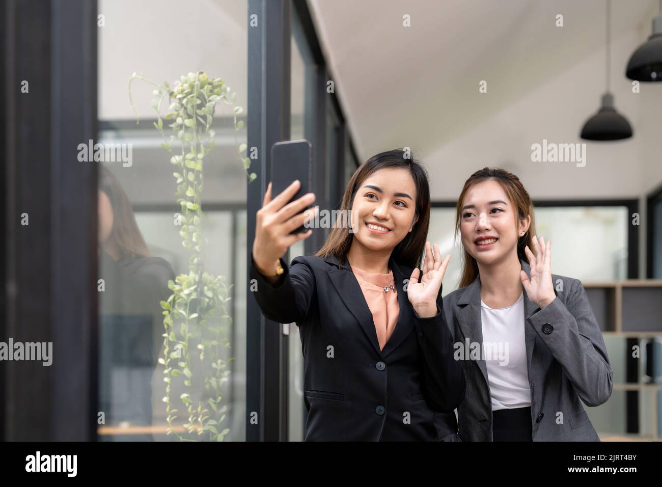 Deux hommes d'affaires asiatiques se sont fait passer la main pour saluer leur partenaire lors d'une vidéoconférence avec son équipe. Banque D'Images