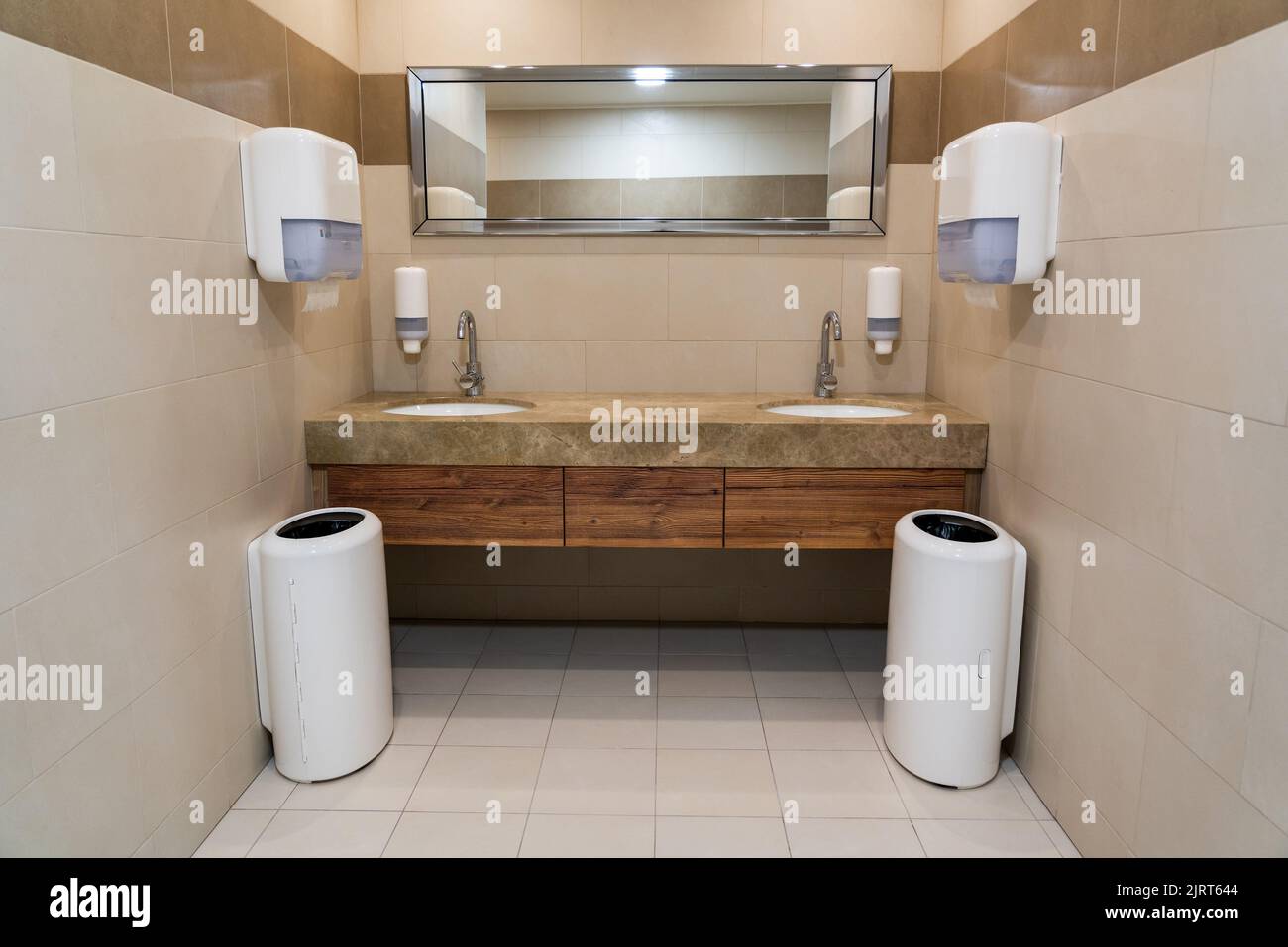 Lavabos symétriques dans une toilette publique moderne avec serviettes en papier et porte-savon Banque D'Images