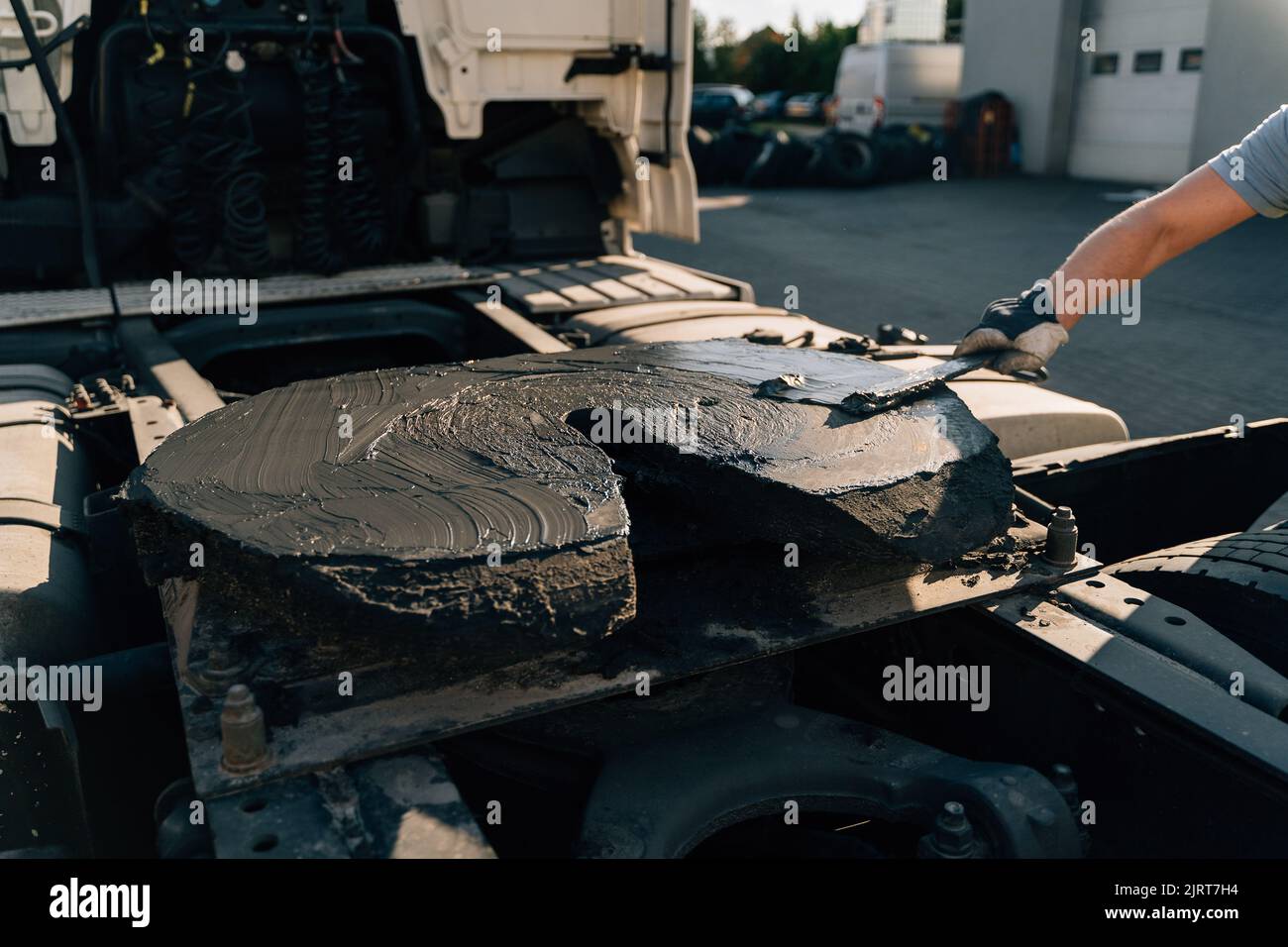 Un employé étalant l'accouplement de la sellette d'attelage avec de l'huile lubrifiante. Entretien mécanique de semi-camions Banque D'Images