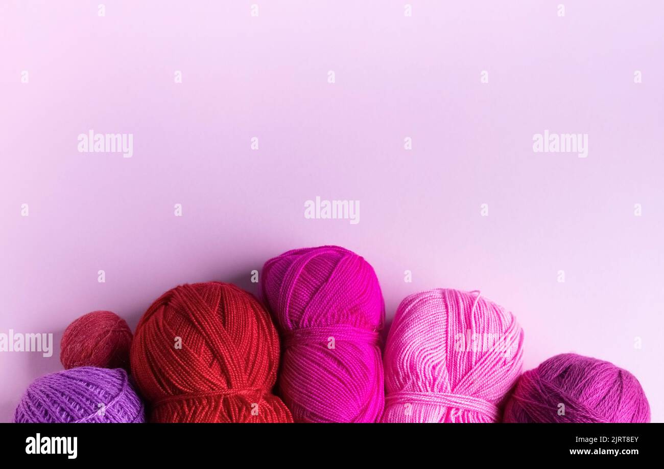 Laine tricotée rose rouge et violet sur fond lilas, passe-temps Banque D'Images