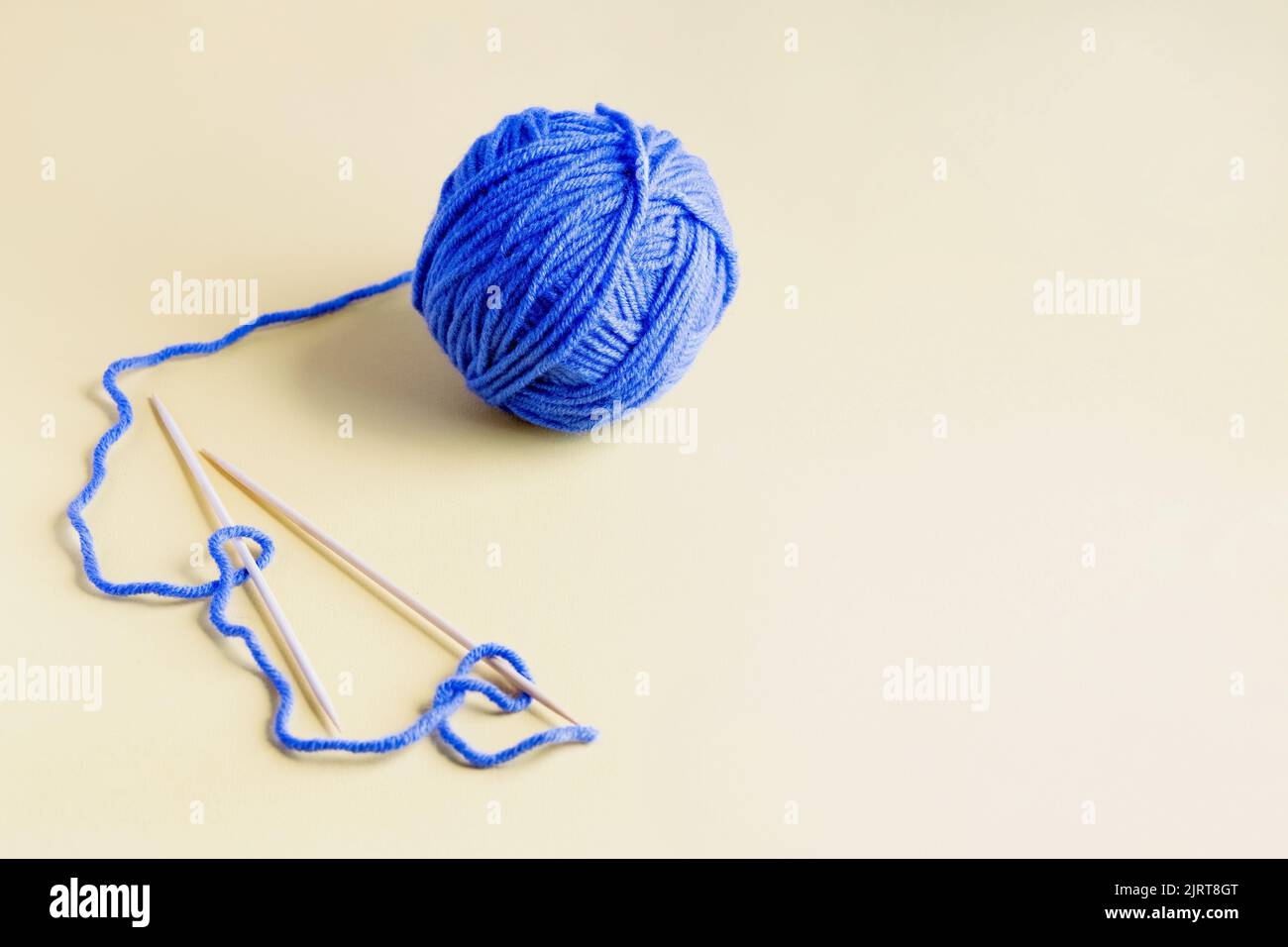 Boule bleue de fils à tricoter avec aiguilles à tricoter sur fond jaune pour tricoter des vêtements chauds Banque D'Images