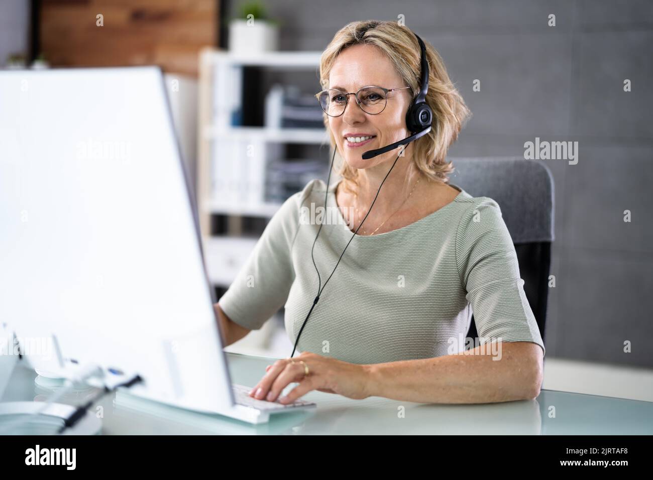 Agent de service commercial avec micro-casque sur l'ordinateur au téléphone Banque D'Images