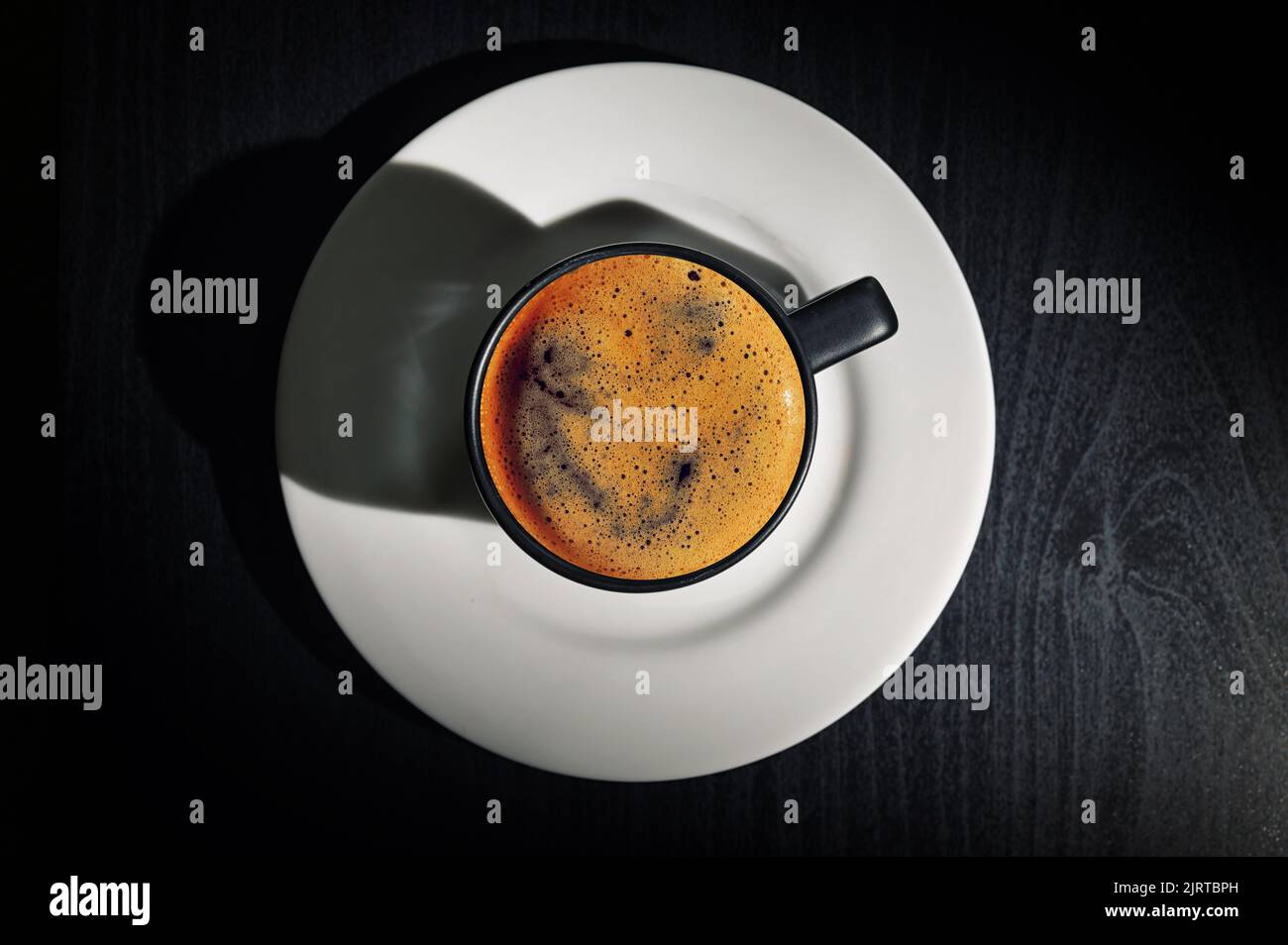 Tasse à espresso noir et ombre sur table noire Banque D'Images