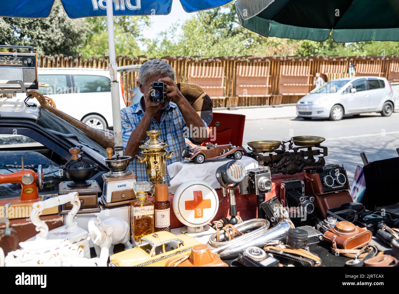 Un drôle de vendeur géorgien sur le marché aux puces posant avec un ancien appareil photo d'époque dans le marché aux puces de Tbilissi Banque D'Images