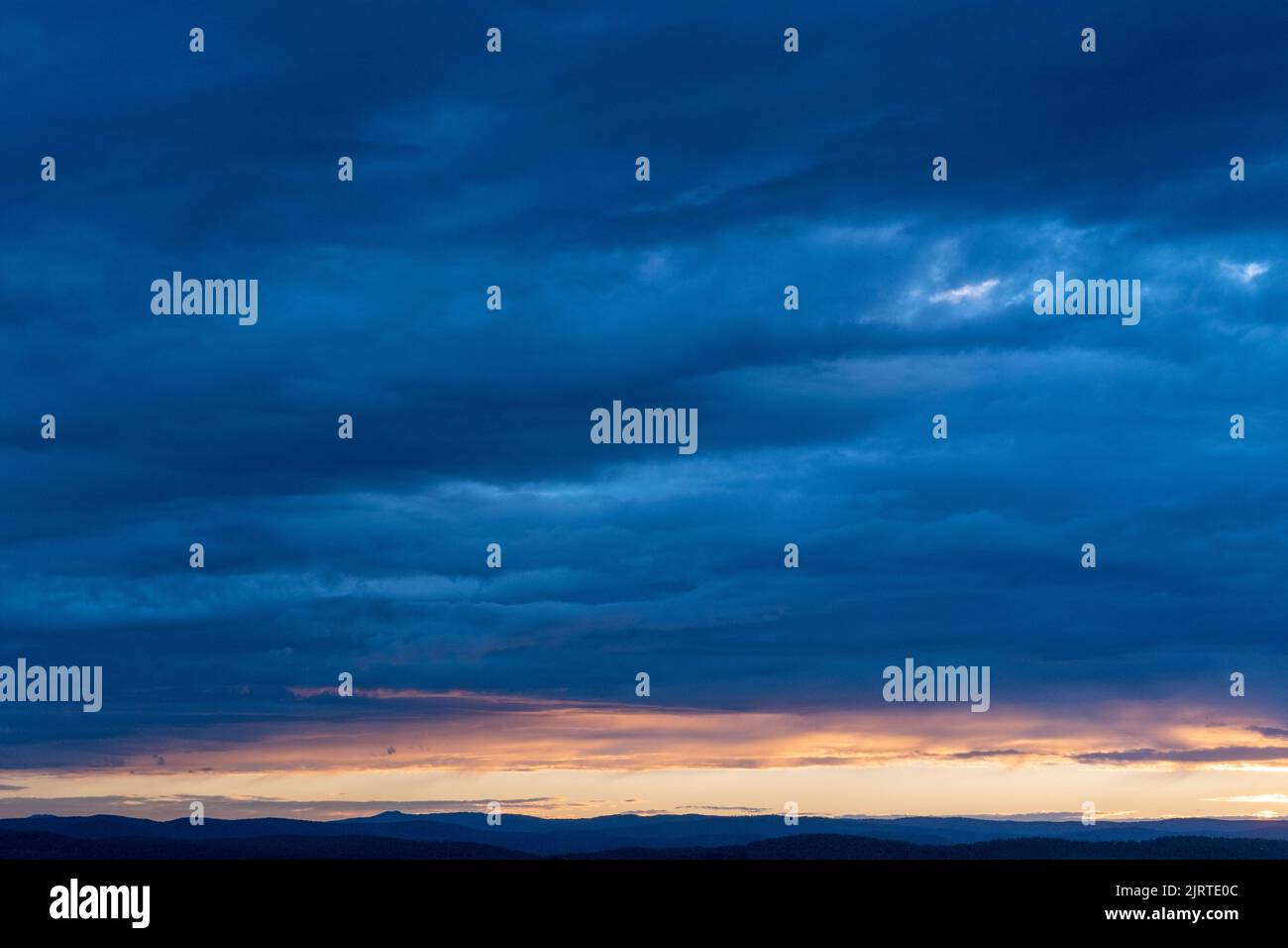 Ciel nocturne avec des nuages éclairés, coucher de soleil incroyable et lumière du soleil majestueuse qui se brisent à travers les nuages et laissant des traînées de rayons sur le fond de Banque D'Images