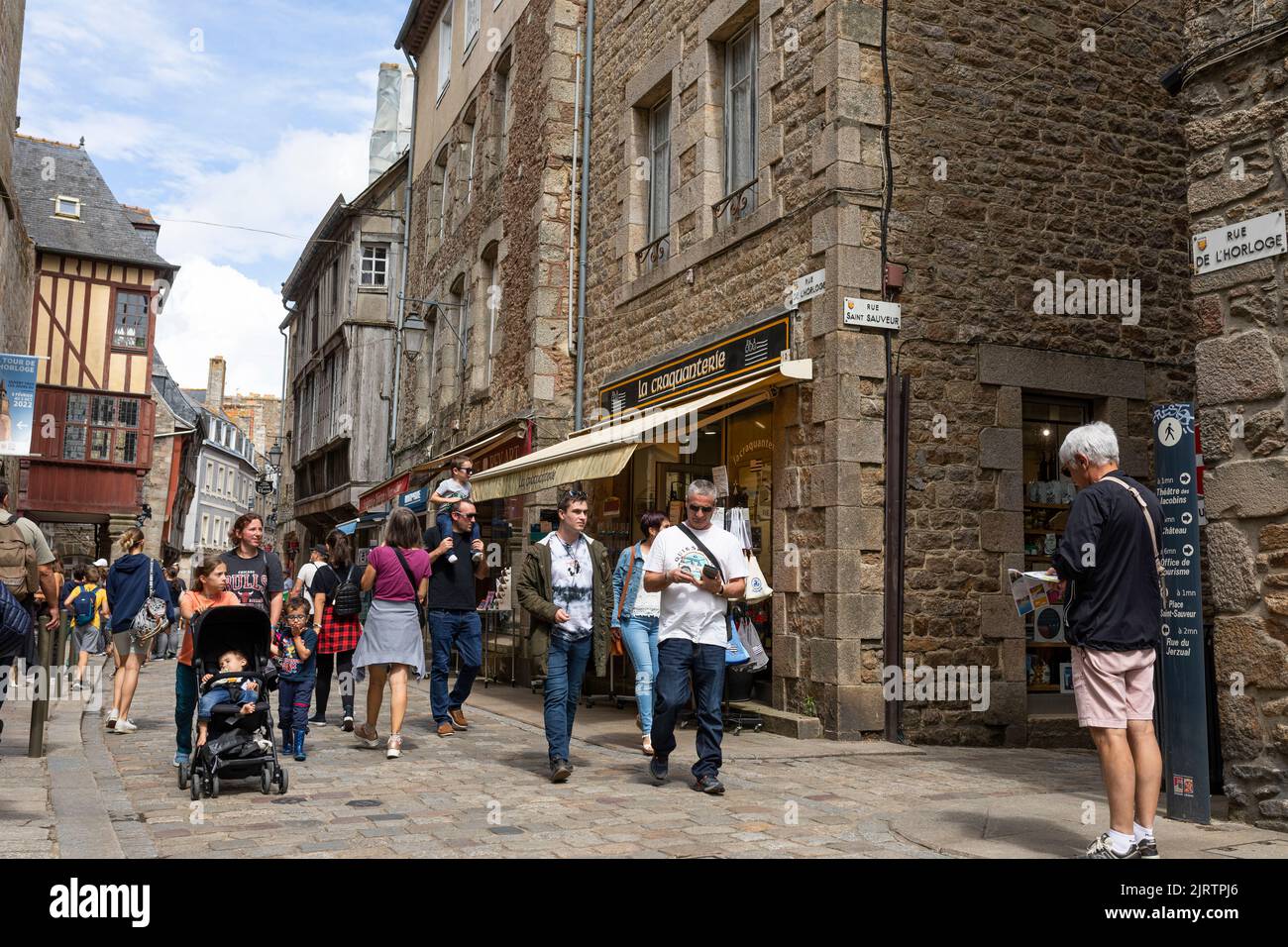 Foule de touristes marchant dans une rue commerçante dans la ville médiévale de Dinan, Bretagne, France Banque D'Images