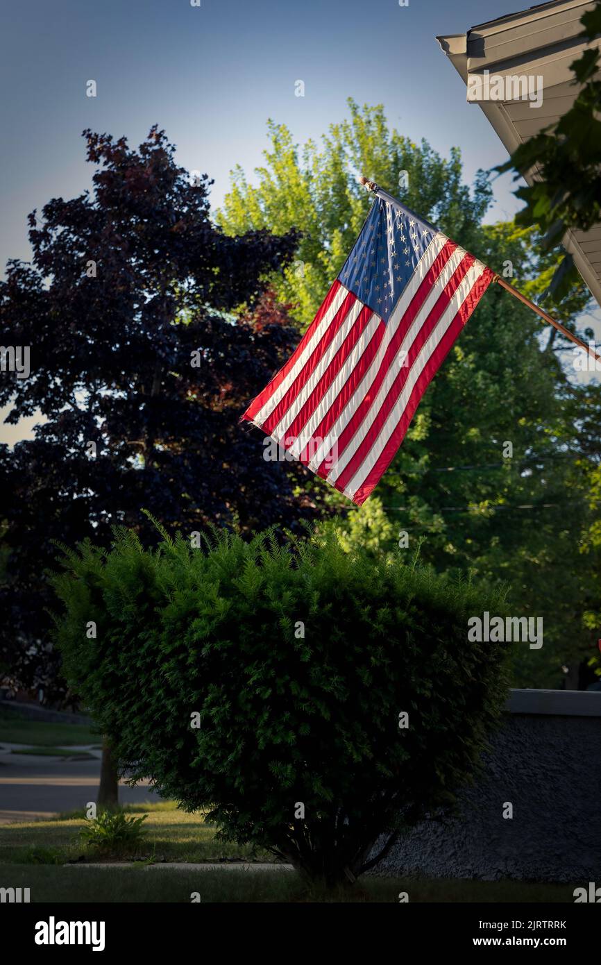 Le soleil du matin brille à travers les arbres sur un drapeau américain à Manitowoc, Wisconsin. Banque D'Images