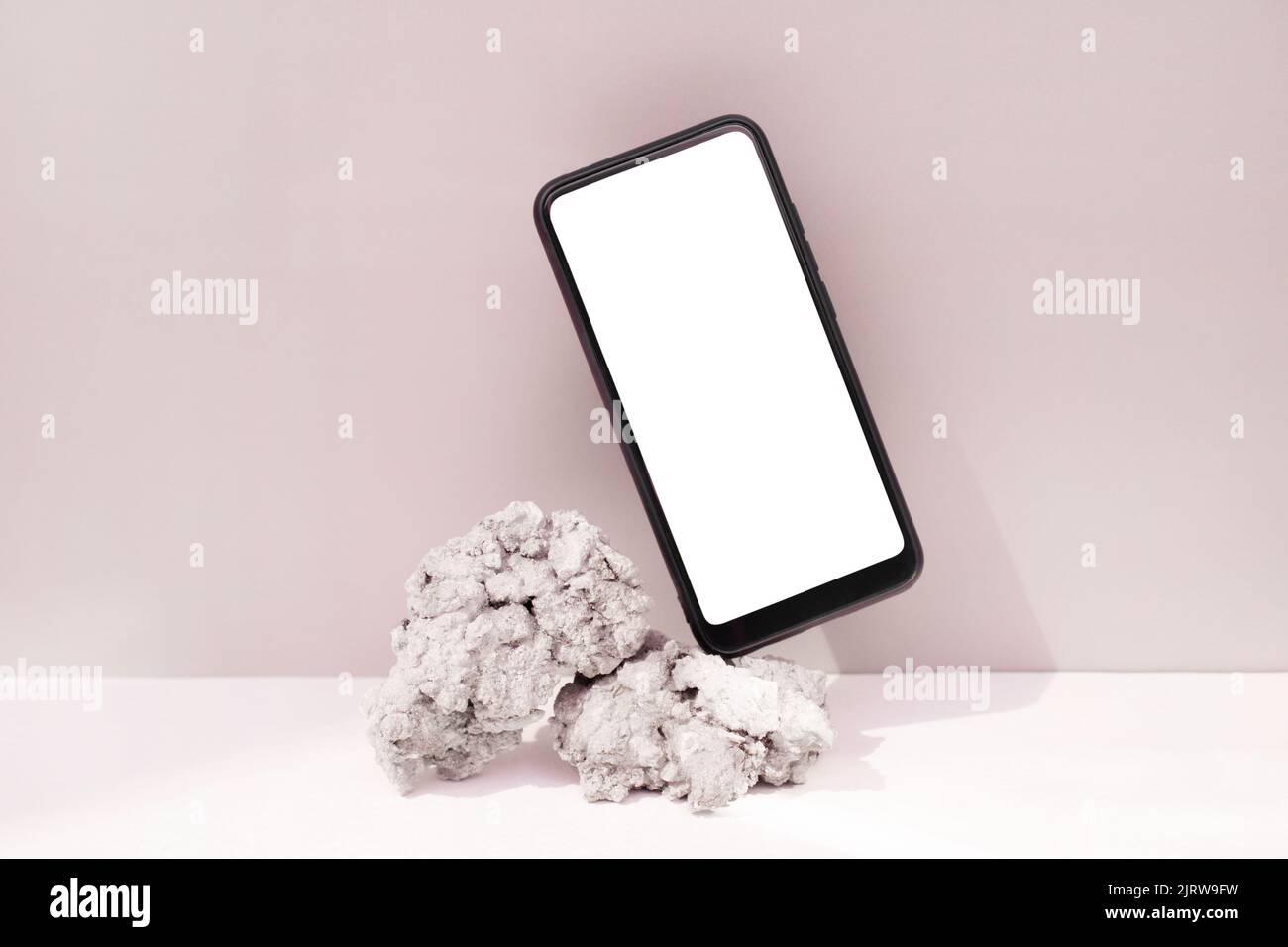 Maquette smartphone équilibre sur pierre naturelle sur fond rose. Téléphone avec modèle d'écran vierge Banque D'Images