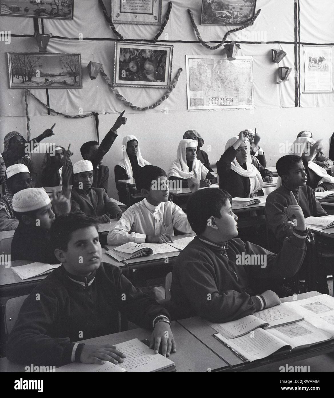 1960s, lycéens arabes historiques en classe, Jeddah, Arabie Saoudite, certains en robe traditionnelle, coiffures. Banque D'Images