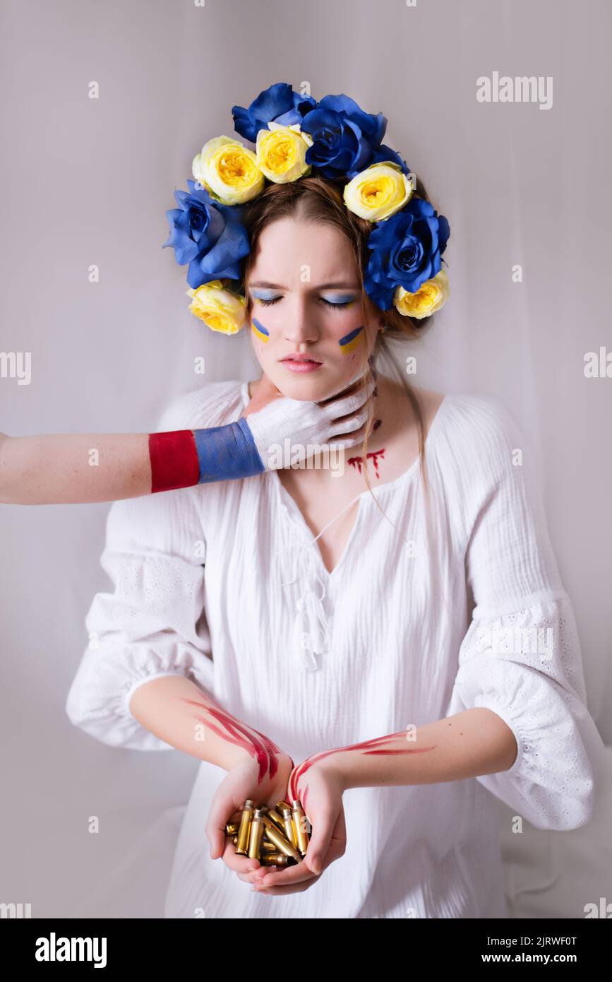 Une jeune femme ukrainienne pendant la guerre avec une couronne bleue jaune de balles et de sang sur un fond blanc de gros plan. La Russie a attaqué l'Ukraine en 2022 Banque D'Images