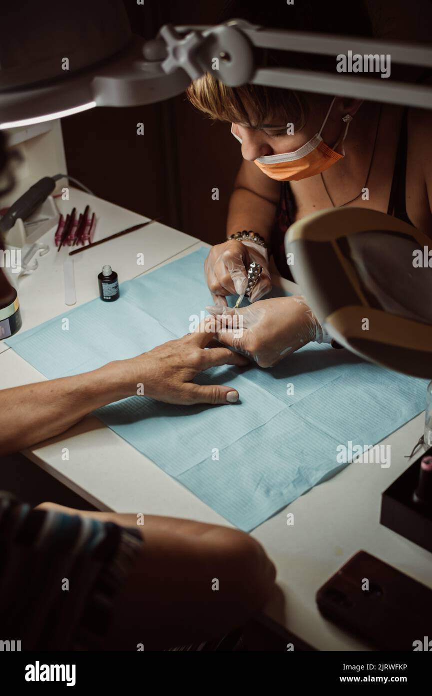 Les mains de manucuriste peignent les ongles sur la main du client avec du vernis Banque D'Images