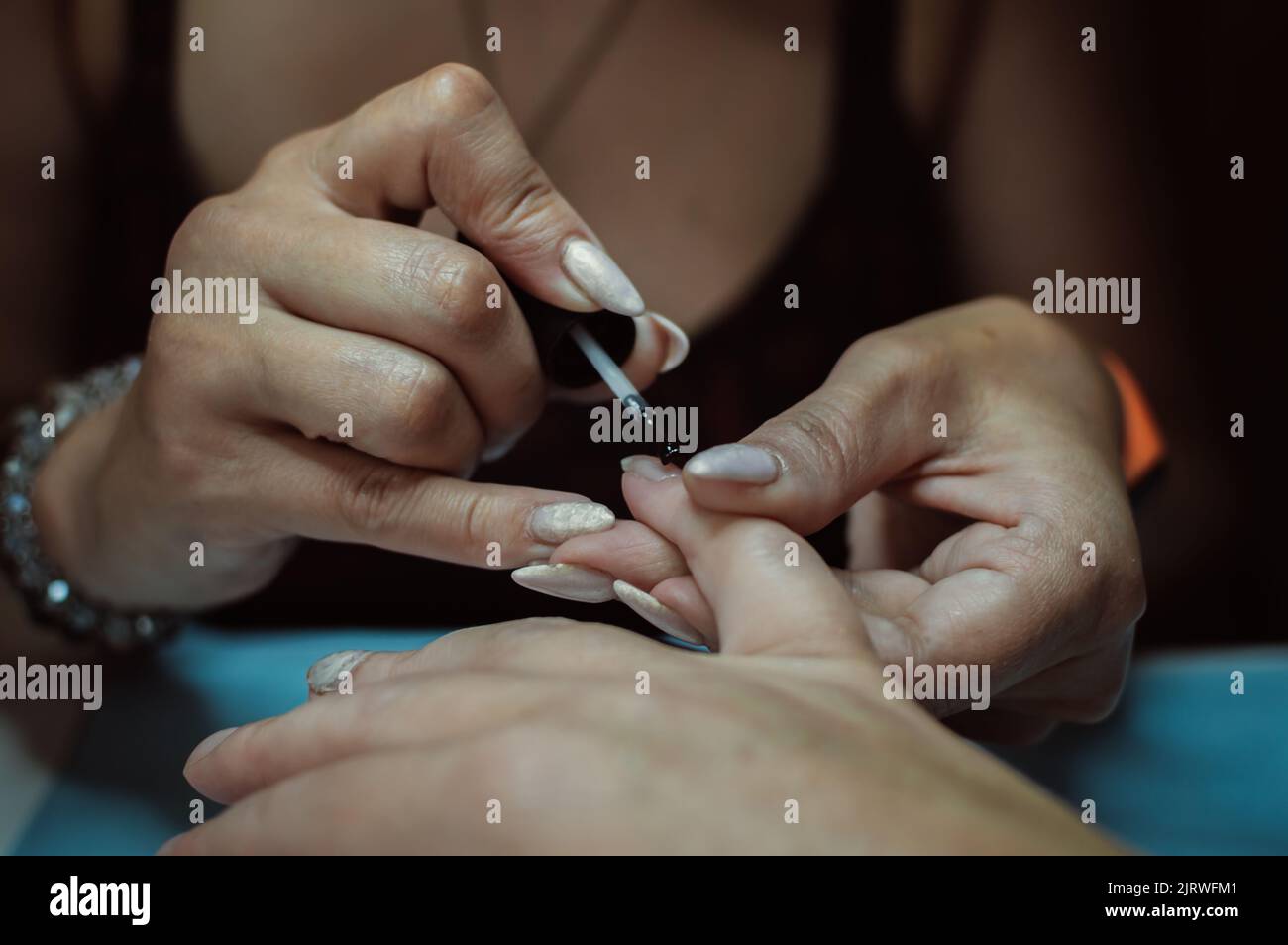 Les mains du manucuriste peignent les ongles sur la main du client avec du vernis Banque D'Images