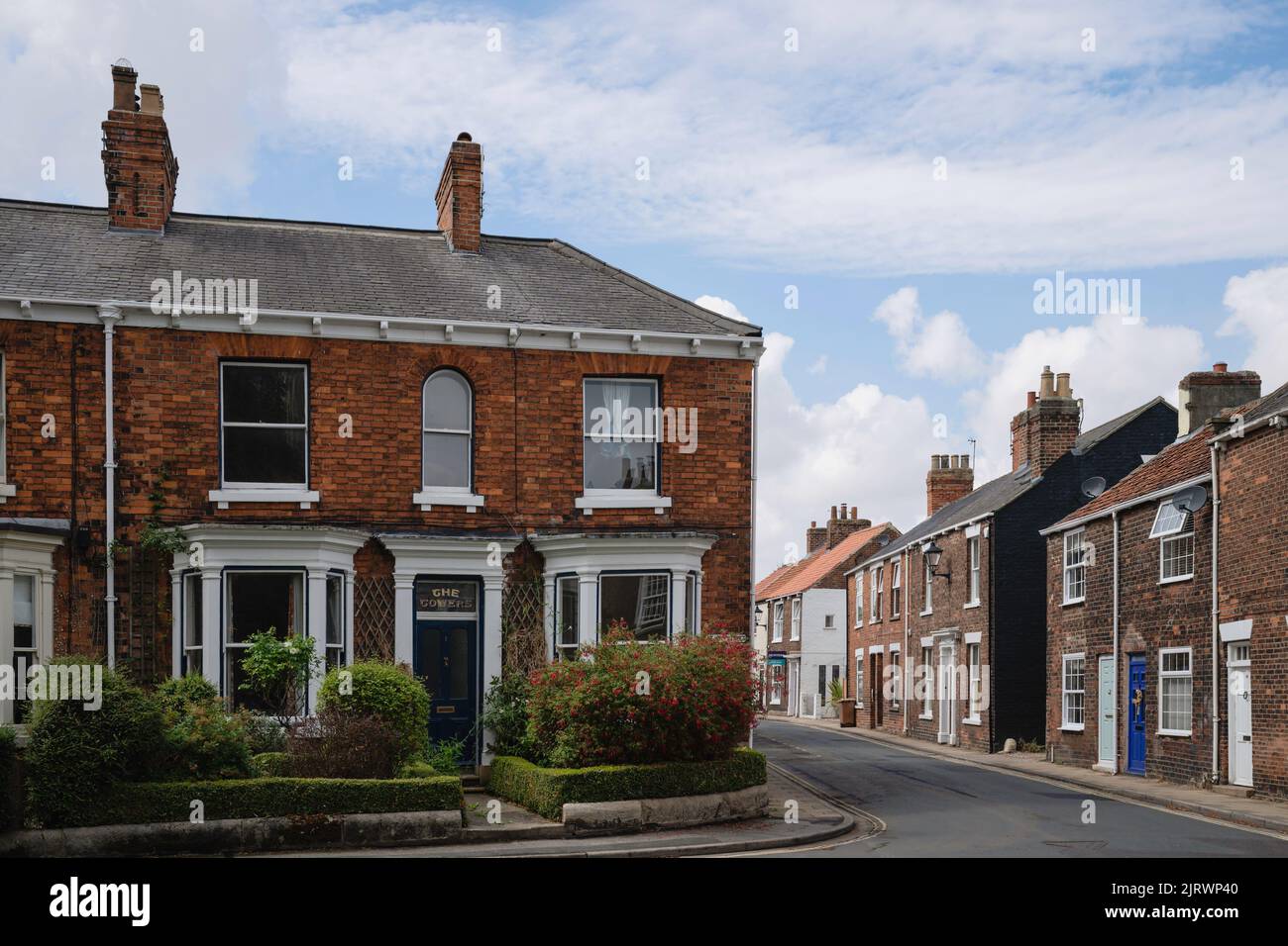 Maisons mitoyennes, dont une avec jardin fleuri, sur la rue St John et Minster Moorgate, toutes sous le ciel bleu à Beverley, Royaume-Uni. Banque D'Images