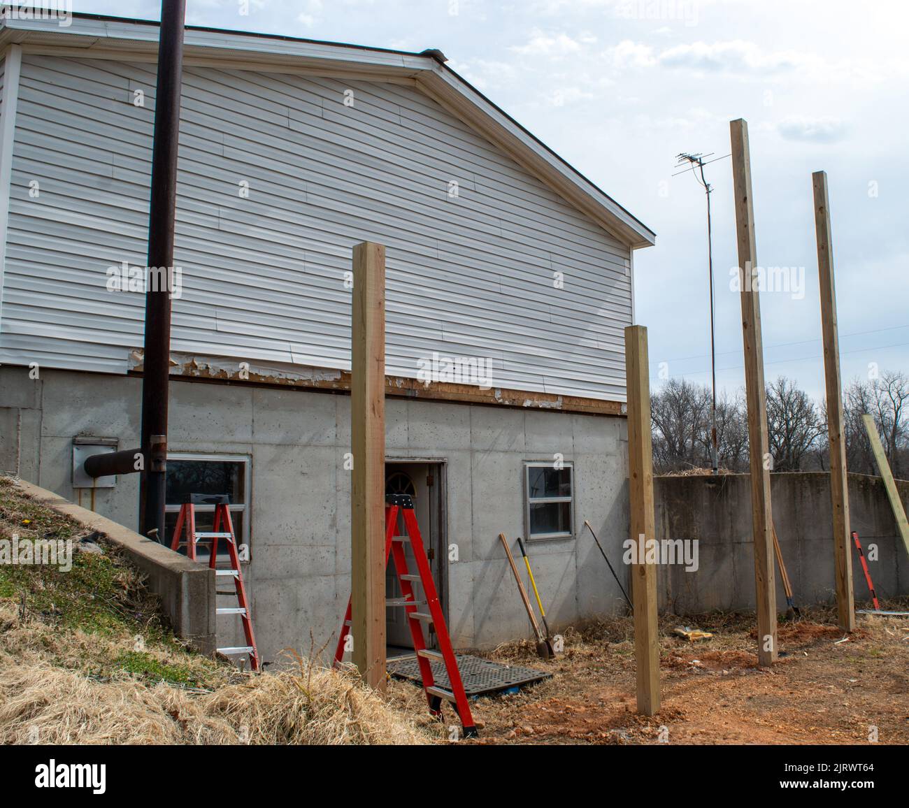 Des trous ont été creusés et les grands poteaux en bois ont été mis dans le sol. La construction d'une nouvelle pièce à l'extrémité de cette maison commencera bientôt. Banque D'Images