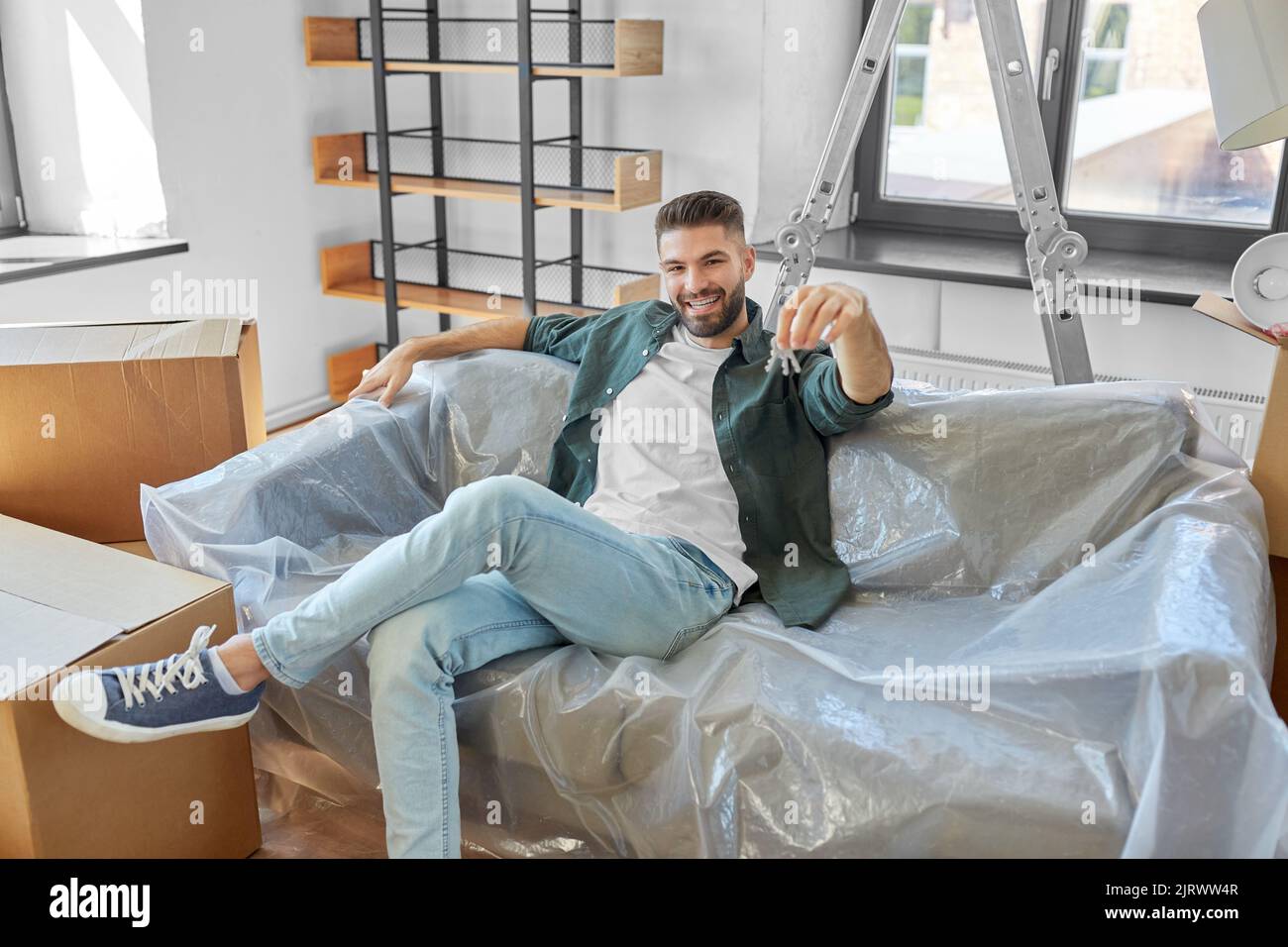 homme avec des clés et des boîtes de maison se déplaçant à la nouvelle maison Banque D'Images