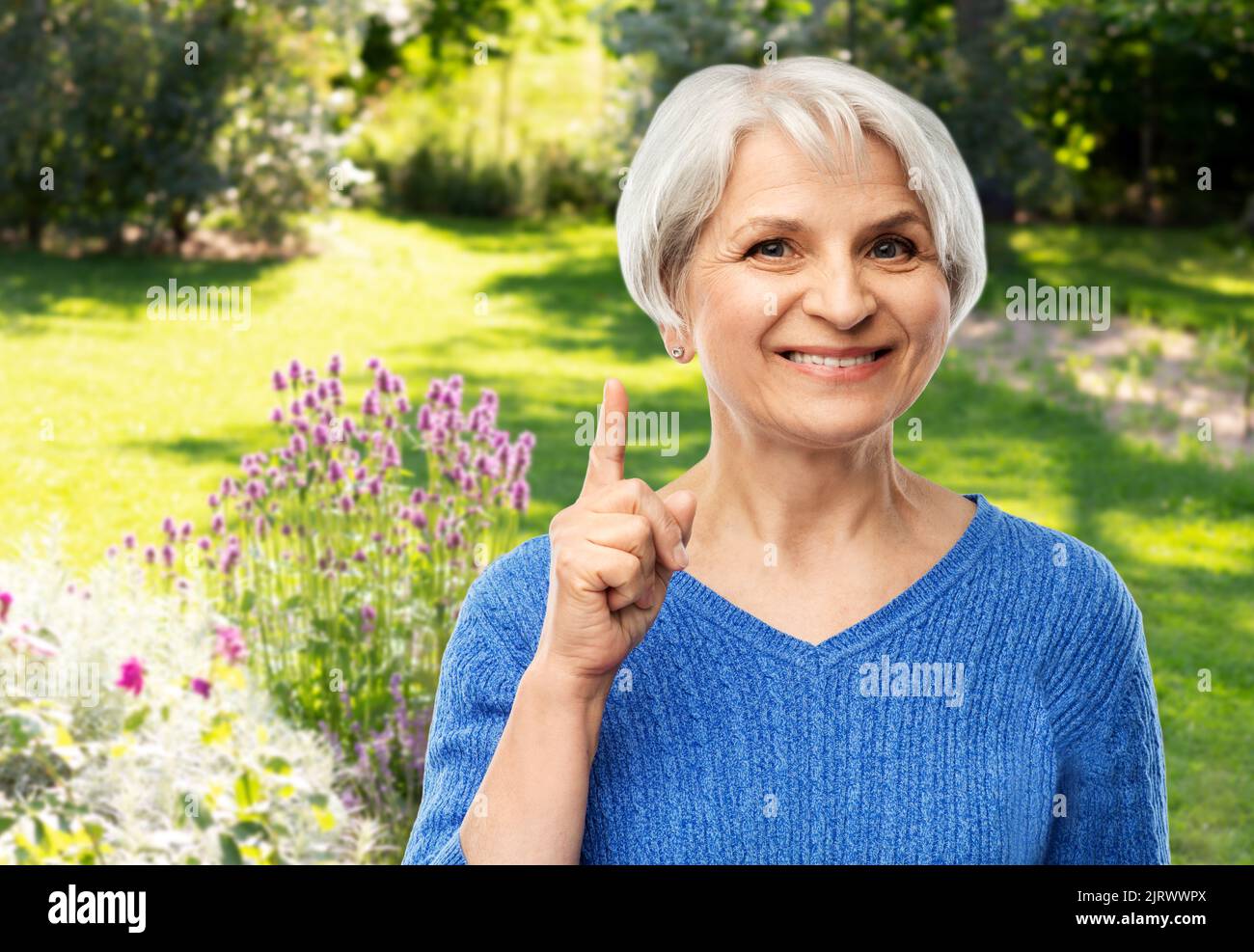 Smiling senior woman pointing finger up Banque D'Images