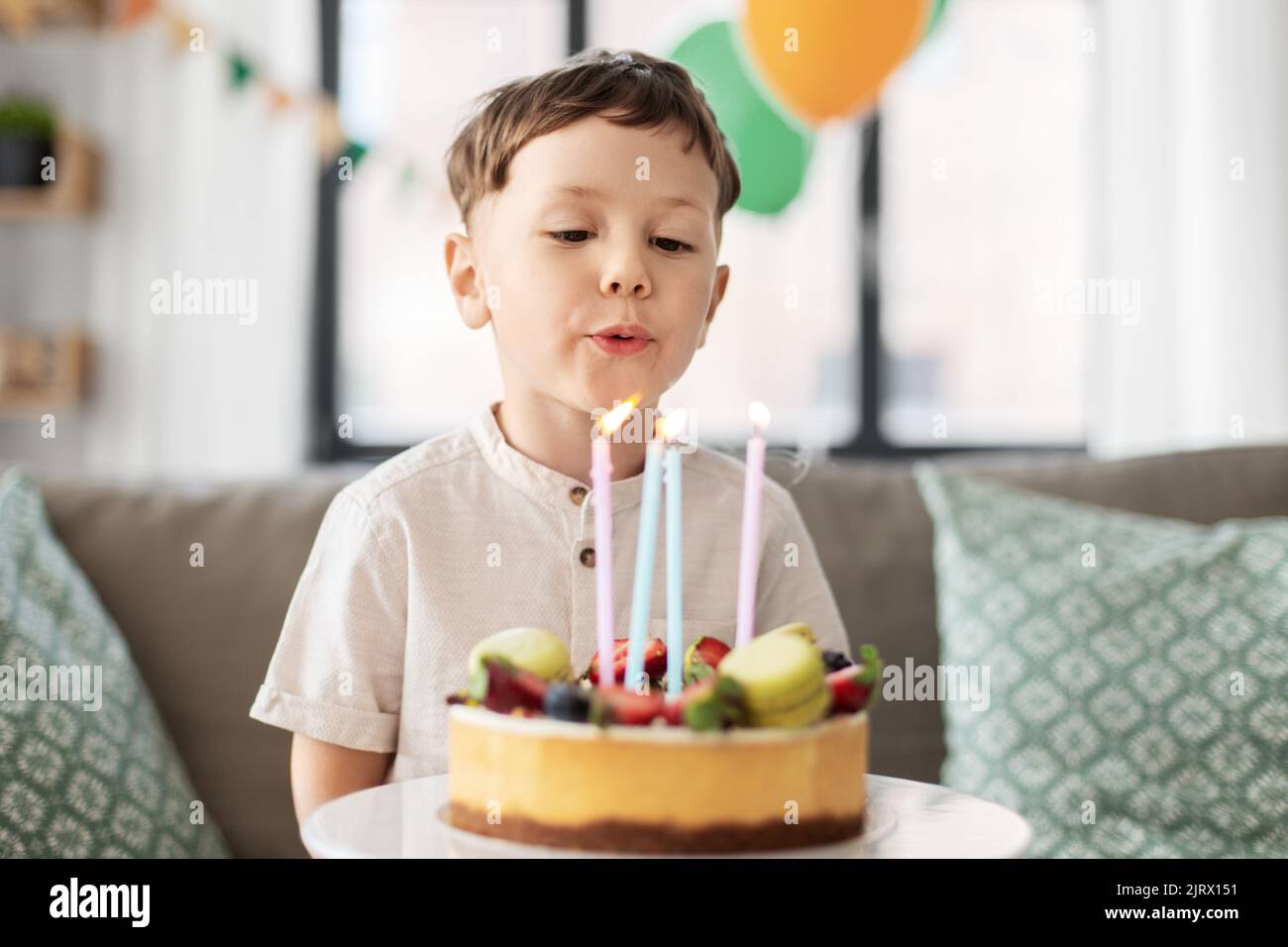 joyeux petit garçon soufflant des bougies sur le gâteau d'anniversaire Banque D'Images