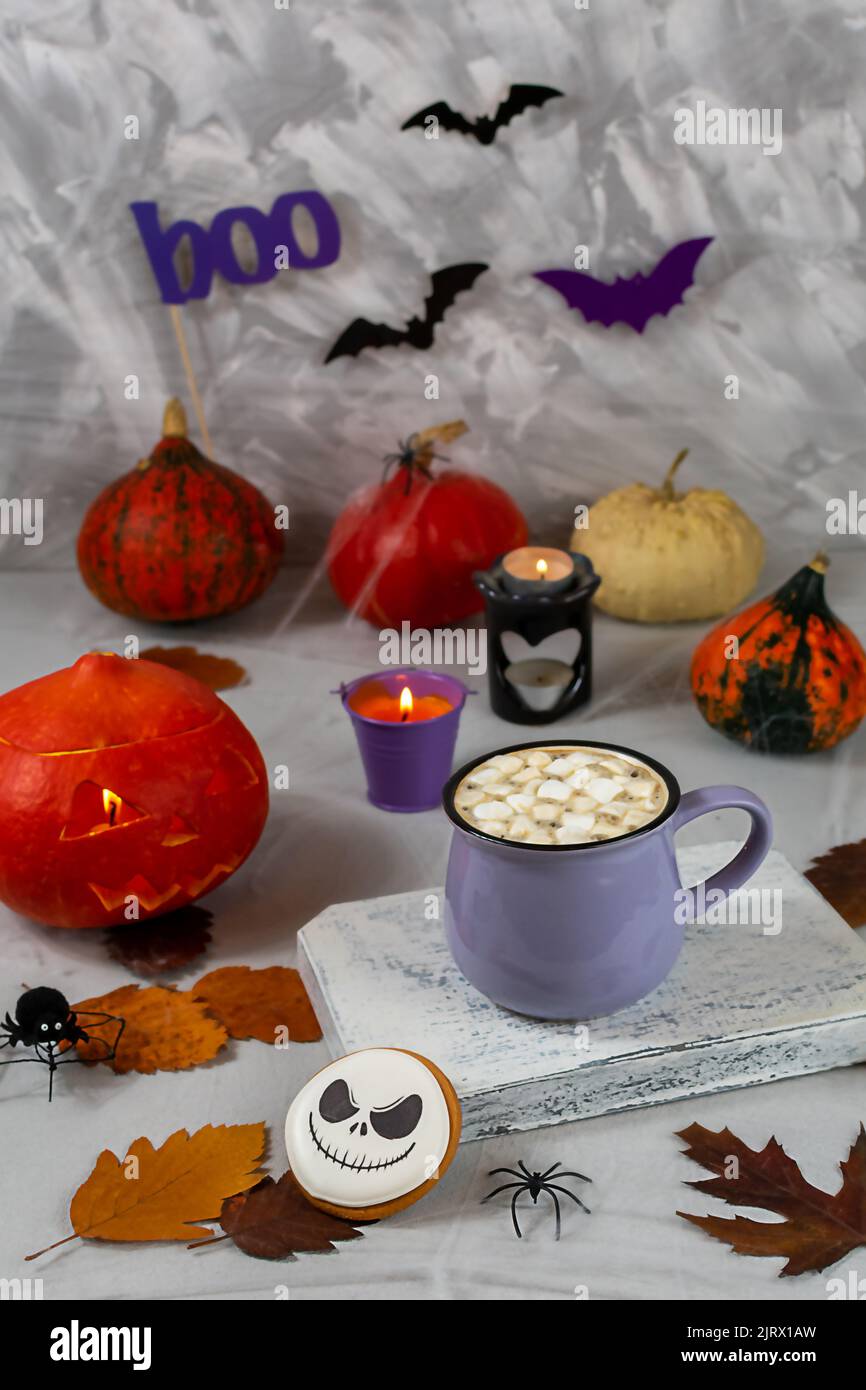 Citrouille d'Halloween et tasse de café avec biscuits sur le fond d'un mur gris avec des fantômes, des chauves-souris, des araignées, des bougies, des citrouilles. Feuilles. Sélectif Banque D'Images