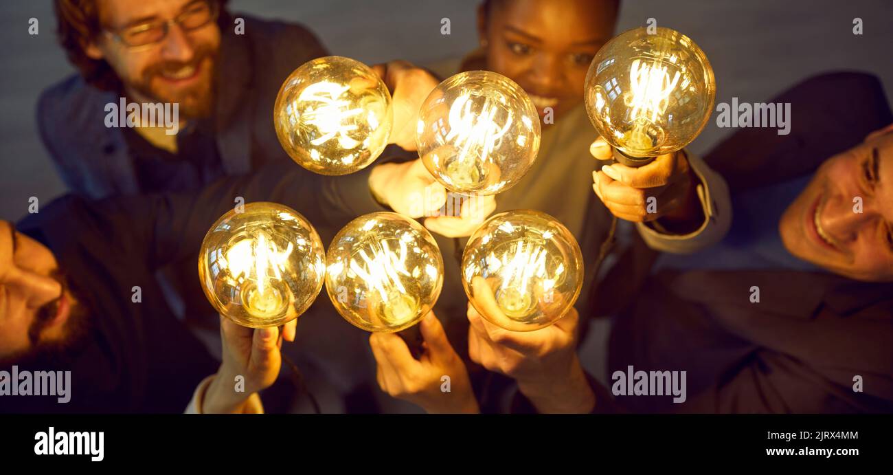 Une équipe d'affaires diversifiée et heureuse avec des ampoules qui développent et partagent de nouvelles idées créatives Banque D'Images
