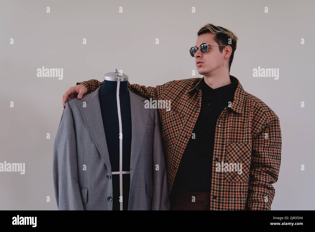 Créateur de mode avec un nouveau vêtement. Couturière travaillant sur un costume gris. Homme de race blanche blonde avec un mannequin sur un fond blanc isolé. Photo de haute qualité Banque D'Images