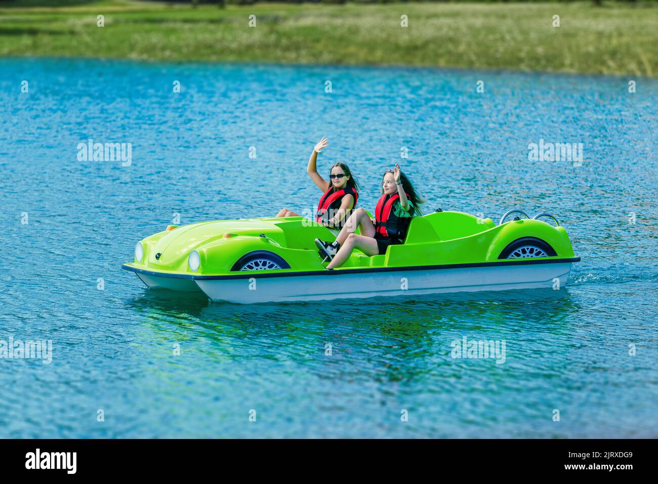 Les filles en vestes de sécurité se délavent et s'embarquent à bord d'un bateau à pédales sur un lac de montagne Banque D'Images