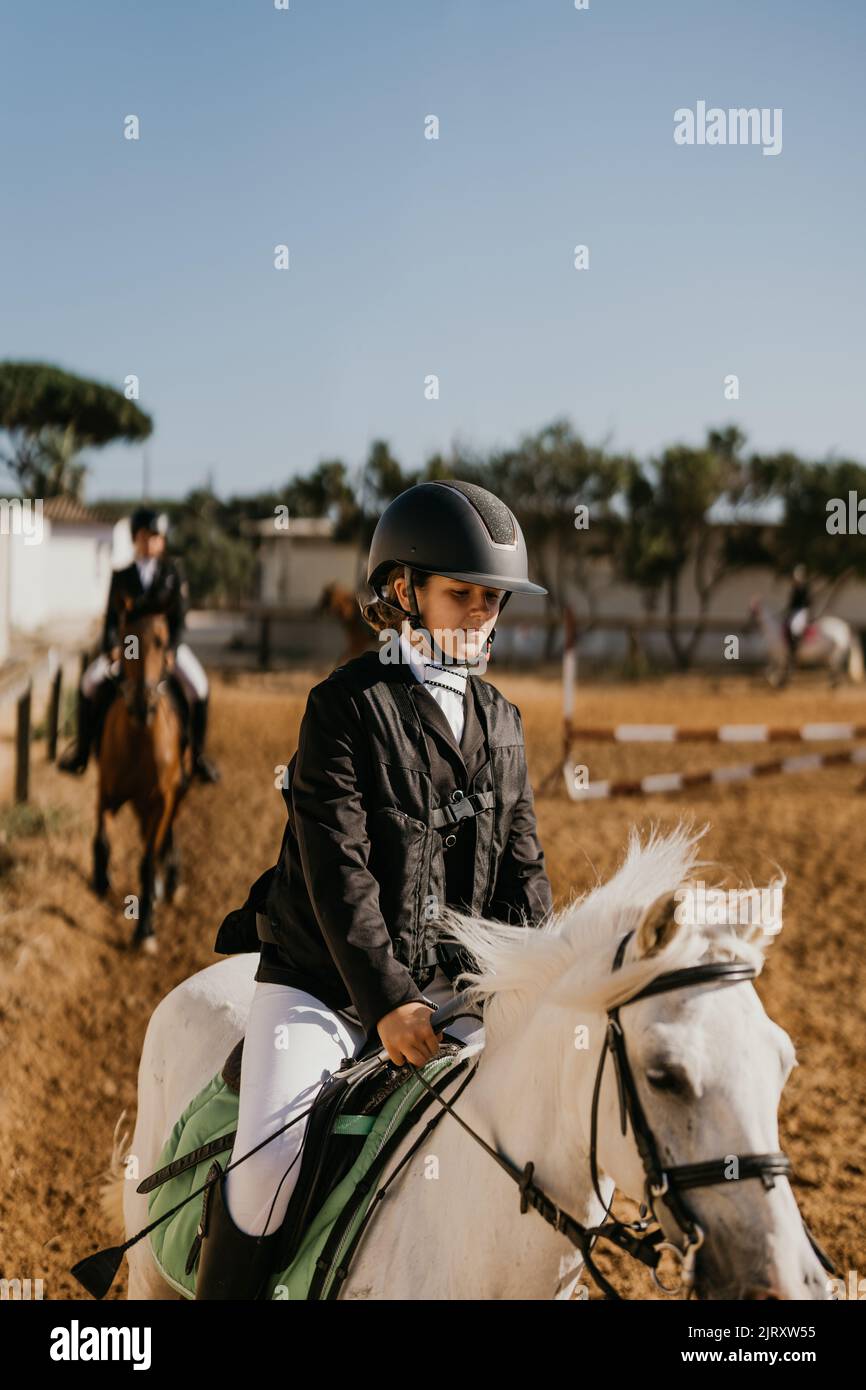 jeune fille de 12 ans qui fait du jogging avec poney blanc à l'école d'équitation Banque D'Images