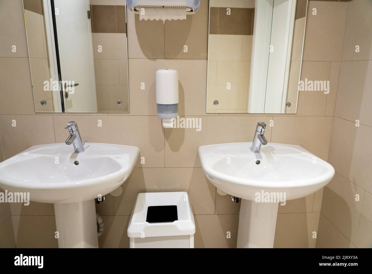 Photo de référence des éviers en céramique dans une salle de bains publique avec un porte-savon et un panier à déchets Banque D'Images