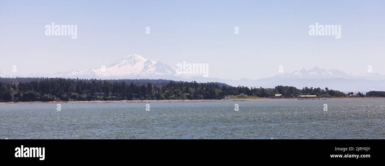 Maisons au bord de la plage sur la côte ouest de l'océan Pacifique avec montagne enneigée Banque D'Images
