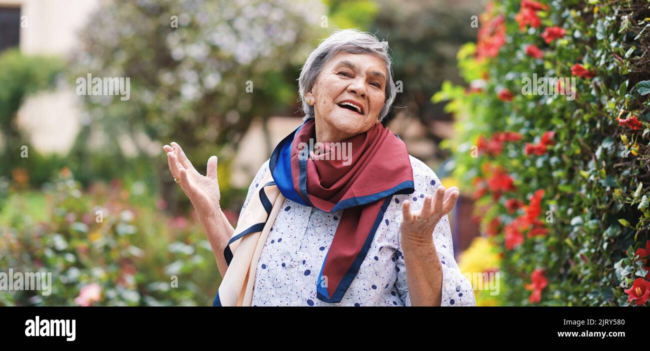 Portrait bonne vieille femme souriante profitant de la retraite en portant un foulard coloré dans un beau jardin Banque D'Images