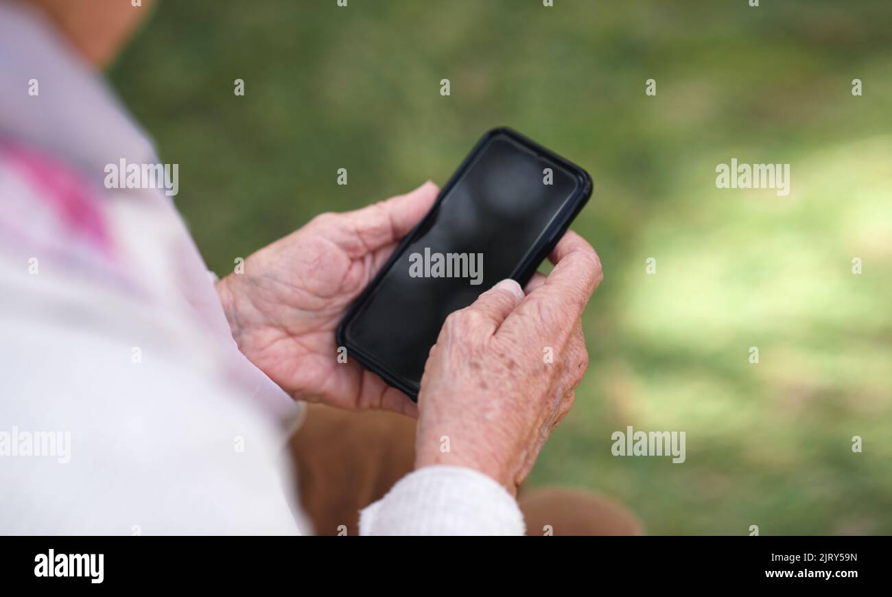 La vieille femme utilise son smartphone pour envoyer des SMS sur son téléphone mobile à l'extérieur Banque D'Images