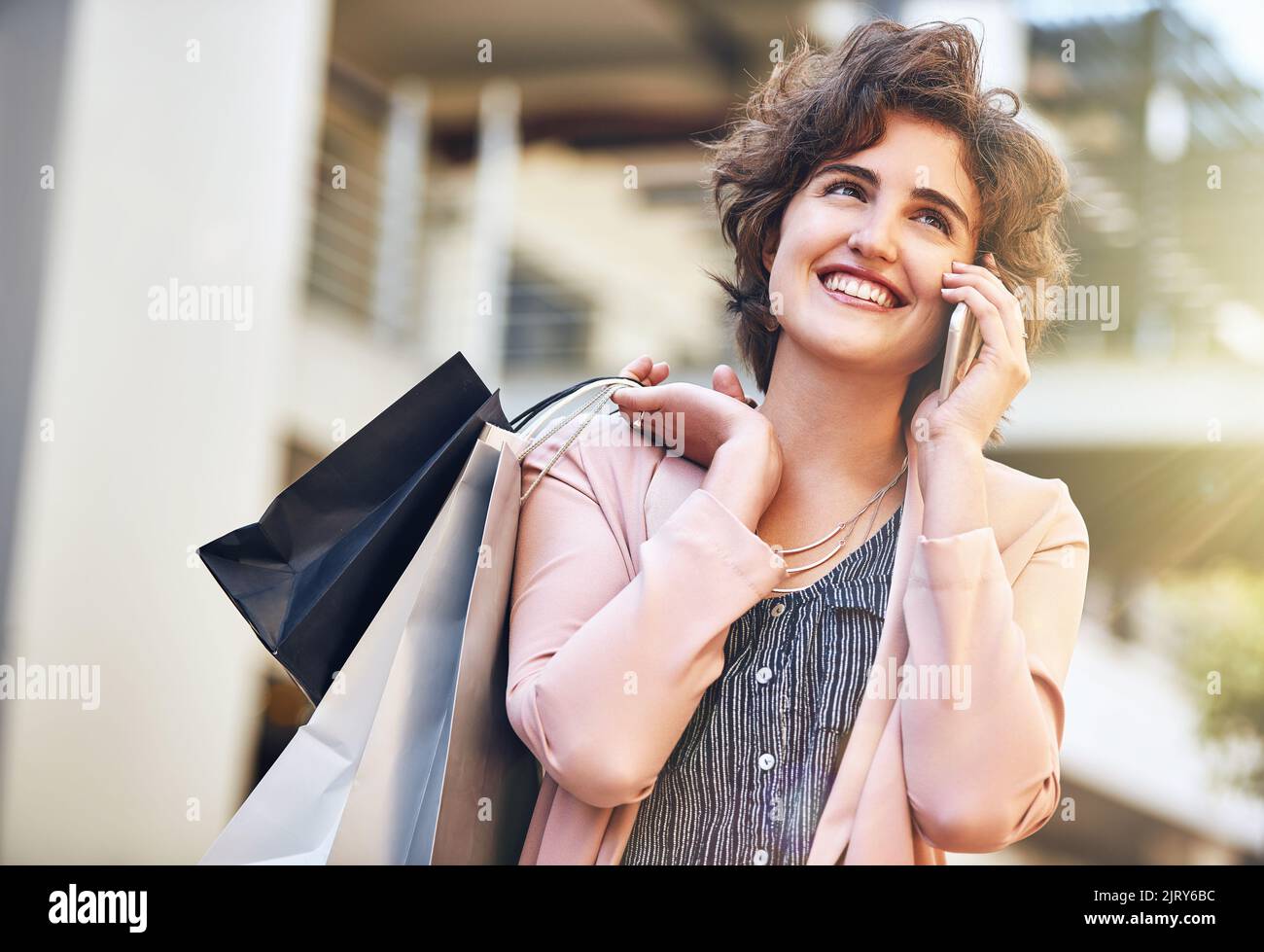 Nous devrions nous habiller et sortir ce soir... une jeune femme qui parle au téléphone tout en faisant du shopping. Banque D'Images