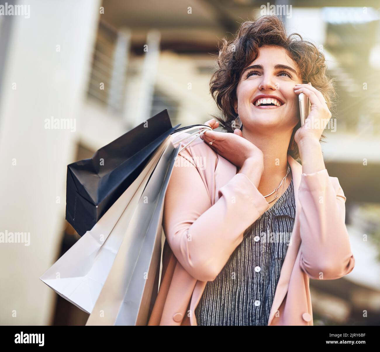Vous avez manqué la plus grande vente. Une jeune femme parlant au téléphone pendant qu'elle fait du shopping. Banque D'Images