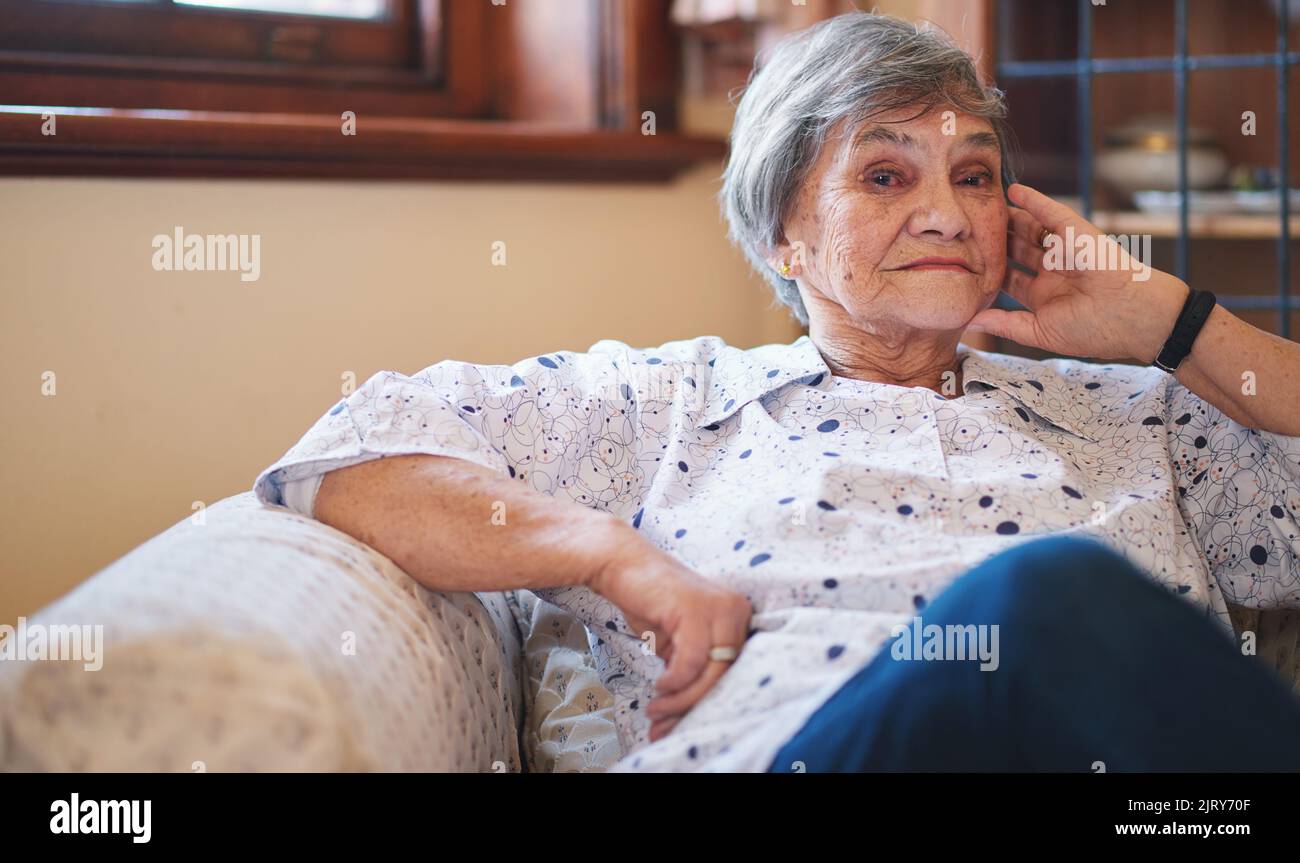 Portrait bonne femme âgée souriante assise sur un canapé à la maison profitant de la retraite Banque D'Images