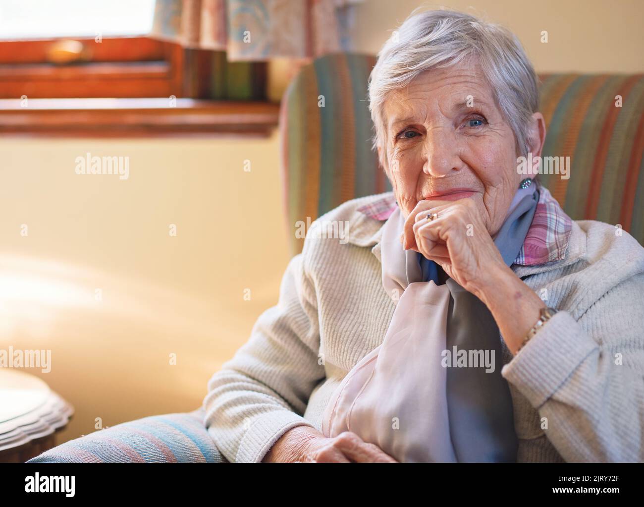 Portrait bonne femme âgée souriante assise sur un canapé à la maison profitant de la retraite Banque D'Images
