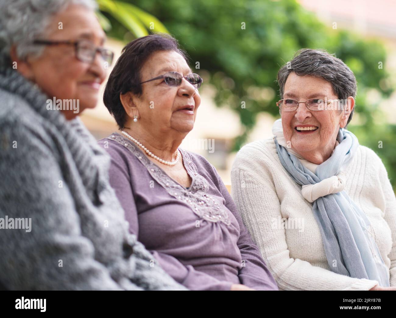 Des femmes âgées heureuses assises sur le banc dans le parc souriant de meilleures amies appréciant la retraite ensemble Banque D'Images