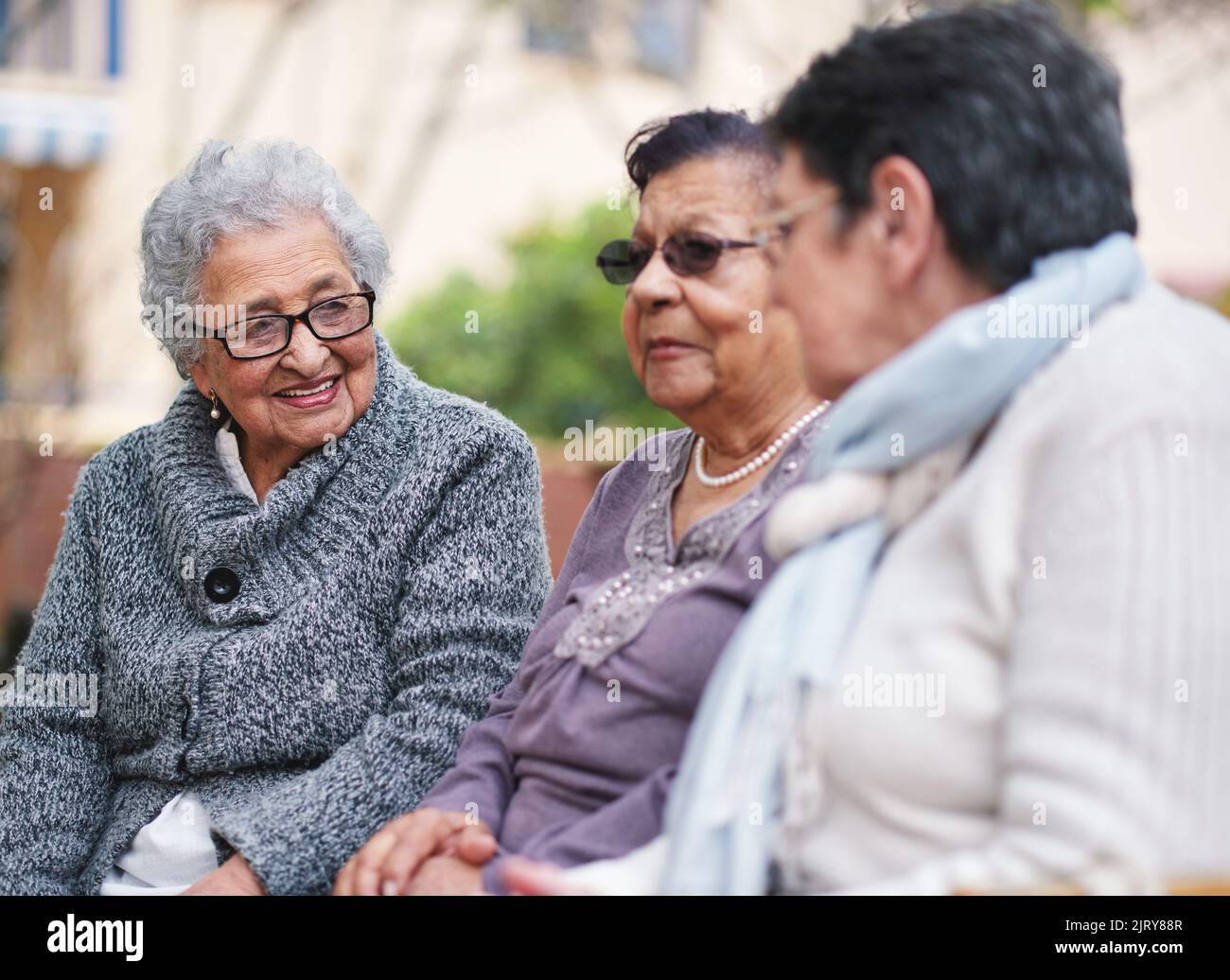 Des femmes âgées heureuses assises sur le banc dans le parc souriant de meilleures amies appréciant la retraite ensemble Banque D'Images