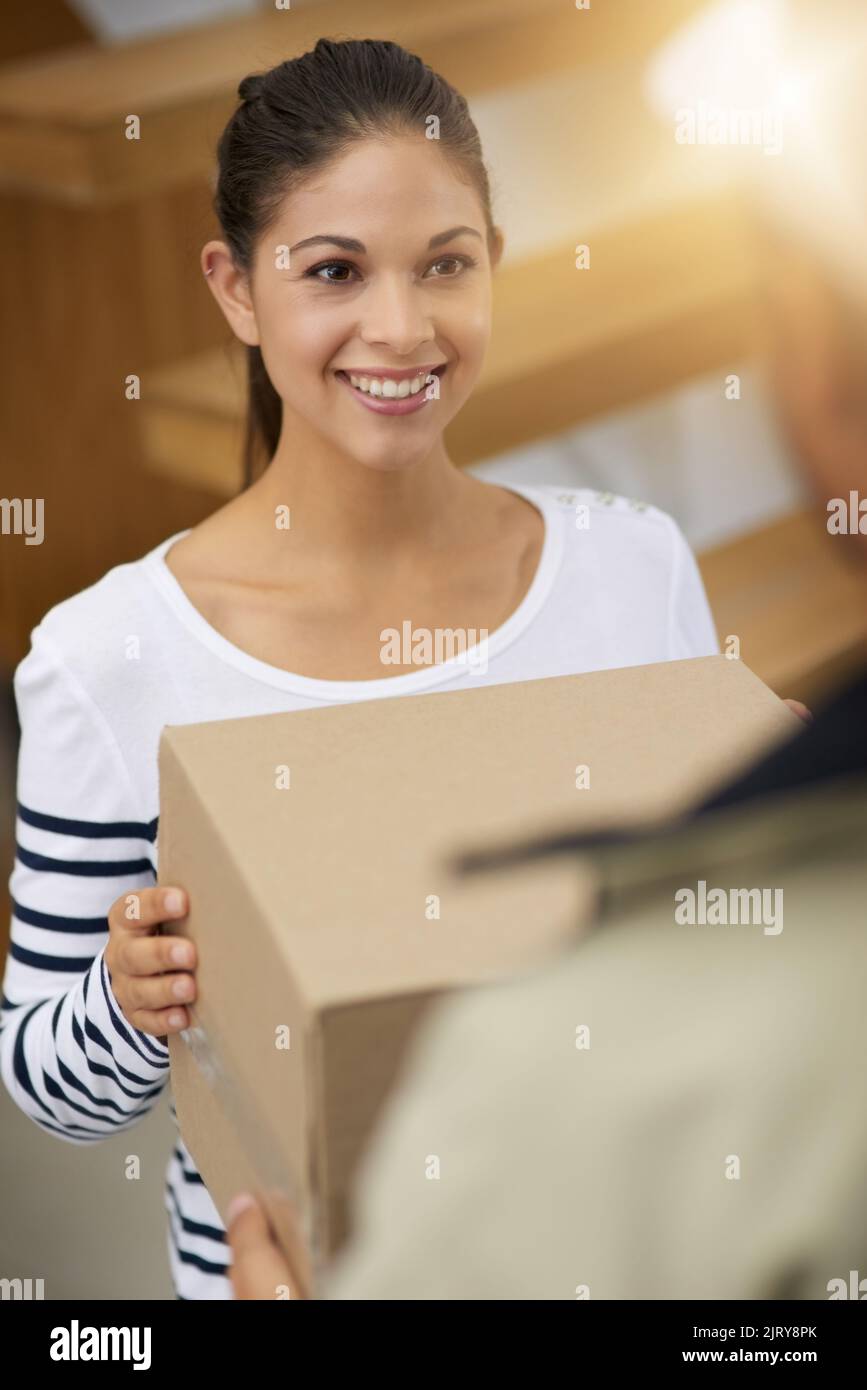 Laisser un autre client satisfait avec un grand sourire. Une jeune femme qui reçoit son colis du service de messagerie. Banque D'Images