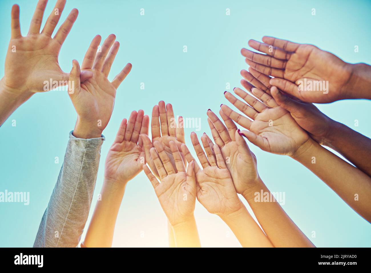 Libérez-vous. Un groupe diversifié de personnes levant les mains dans l'air. Banque D'Images