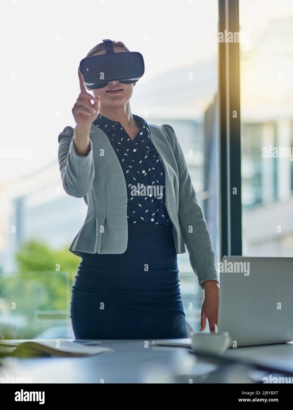 Faire des affaires au-delà des frontières avec la réalité virtuelle. Une jeune femme d'affaires portant un casque de réalité virtuelle au travail. Banque D'Images