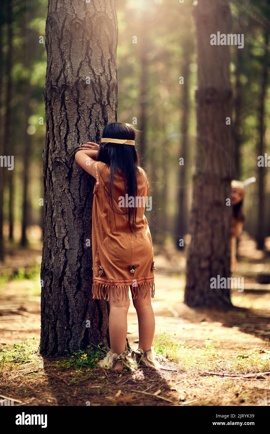 Prêt ou pas, ici je viens. Les petites filles jouant cacher et aller chercher dans les bois tout en habillée comme des Indiens rouges. Banque D'Images