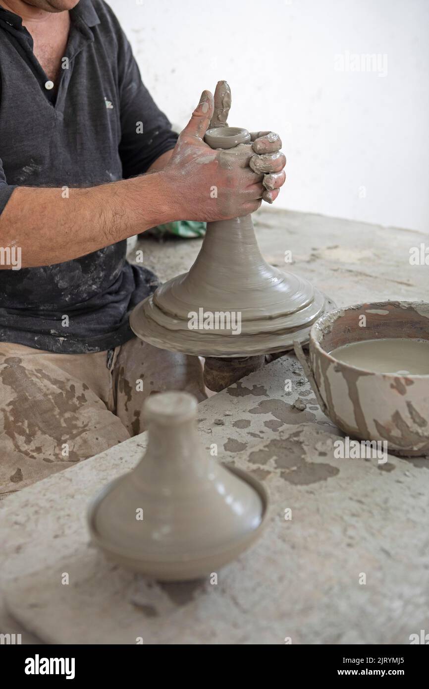 potier marocain à l'œuvre : tourner au panneau du potier et façonner les récipients en céramique et la poterie : cruches, assiettes dans l'atelier du potier, artisanat Banque D'Images