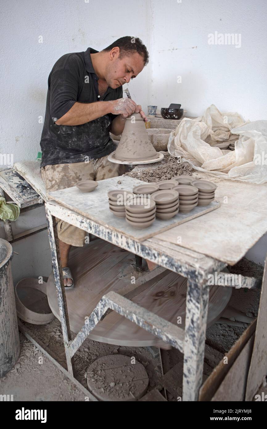 potier marocain à l'œuvre : tourner au panneau du potier et façonner les récipients en céramique et la poterie : cruches, assiettes dans l'atelier du potier, artisanat Banque D'Images