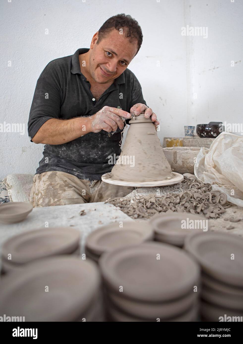 potier marocain à l'œuvre : tourner au panneau du potier et façonner les récipients en céramique et la poterie : cruches, assiettes dans l'atelier du potier, artisanat Banque D'Images